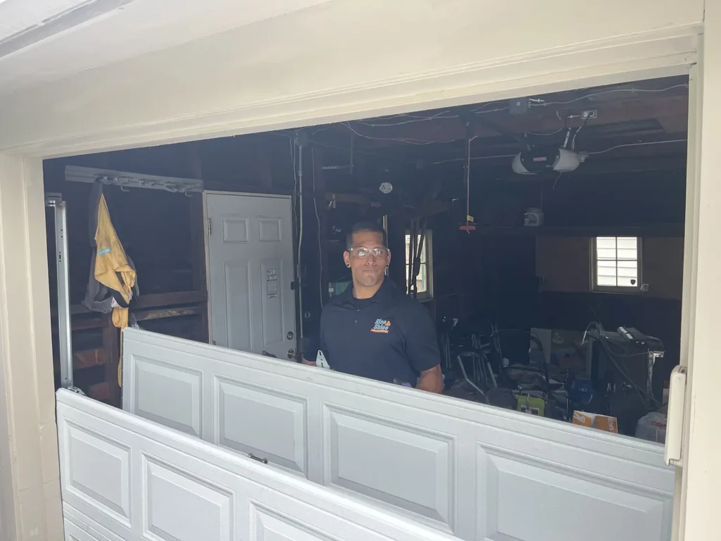 Technician installing garage door inside workshop.